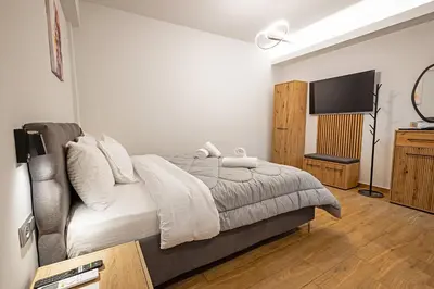 a bedroom with a bed and a flat screen tv at Gina's Apartments in Spáta