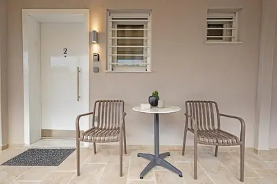 two chairs and a table in a room with a door at Gina's Apartments in Spáta