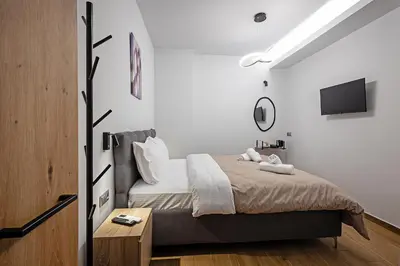 a bedroom with a bed and a tv on the wall at Gina's Apartments in Spáta
