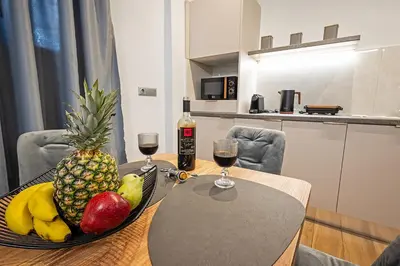 a table with a bowl of fruit and two glasses of wine at Gina's Apartments in Spáta