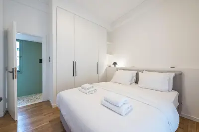 a white bedroom with a large white bed with towels on it at Athens Lyrics in Athens