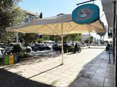 aige umbrella sitting on a sidewalk next to a street at Glyfada Center Apt 11 in Athens