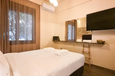 a bedroom with a white bed and a television at Kallithea Cozy Stonewall Studios in Athens