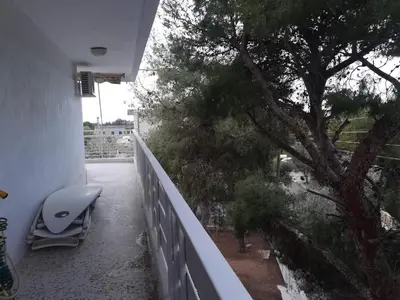 a balcony with a bench and a tree at Sunny with terrace around, sea view, 65 sqm in Saronida