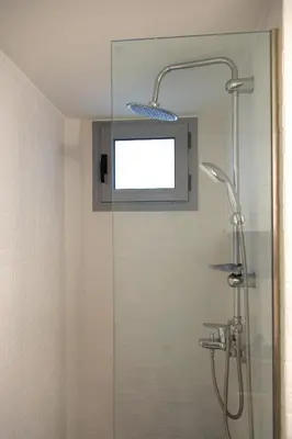 a shower with a glass door and a window at Central Urban Retreat in Athens