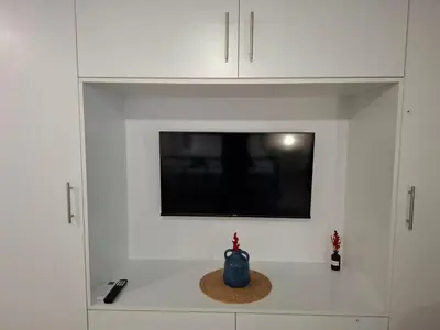 a tv in a white cabinet with a blue vase at Iliana's Retreat by Greece Apartments in Athens