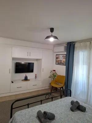 a bedroom with a tv and a bed and a chair at Iliana's Retreat by Greece Apartments in Athens