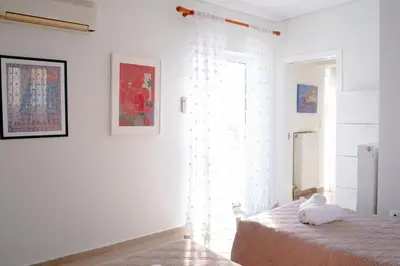 a white bedroom with a bed and a window at Elegant Athenian Penthouse in Athens