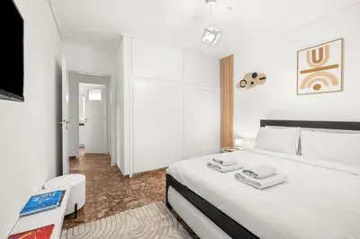 a white bedroom with a bed and a tv at Boho Coastal Retreat with Jacuzzi, 1 min to Beach in Athens