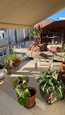 a patio with potted plants and a bed on a balcony at 7th floor bright penthouse in quiet pedestrian in Athens