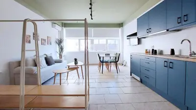 a kitchen and living room with blue cabinets and a table at Modern comfort and city vibes just steps from Athe in Athens