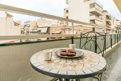 a table with a plate of food on a balcony at Elegant & Modern 2BR Apartment - Pireaus Center and Marina in Piraeus