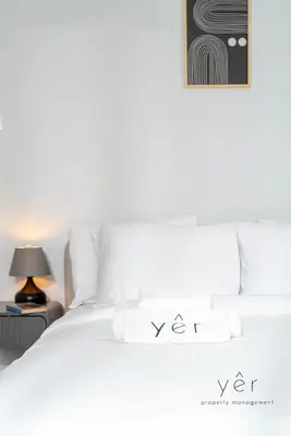 a white bed with white pillows and a lamp at Elegant & Modern 2BR Apartment - Pireaus Center and Marina in Piraeus