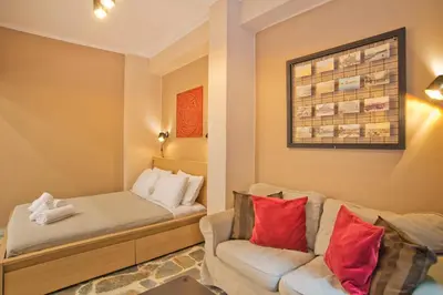 a room with a couch and a bed with red pillows at Alex Guesthouse Stylish Studio near the Sea in Piraeus