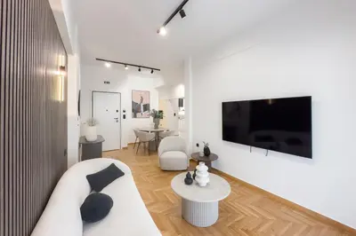 a living room with a white couch and a tv at Athenian Zen Suite in Athens
