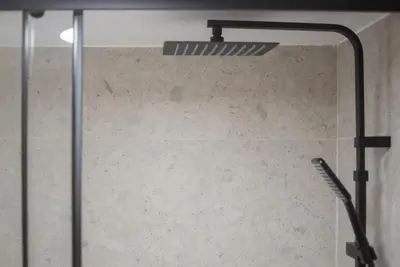 a glass shower door with a shower head at Athenian Zen Suite in Athens