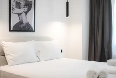 a bed with white sheets and pillows in a room at Athenian Zen Suite in Athens