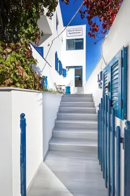 a staircase leading up to a white building with blue doors at Villa El Greco Apartments in Agia Marina Aegina