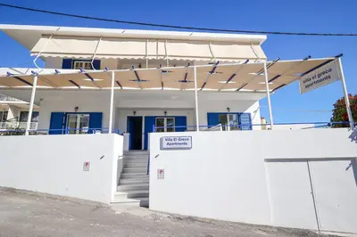a white house with awning in front of it at Villa El Greco Apartments in Agia Marina Aegina