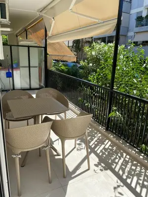 a patio with two tables and chairs and an umbrella at Beach side Marina Alimos apartment in Athens