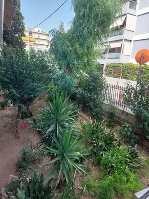 a garden with plants and trees in front of a building at Beach side Marina Alimos apartment in Athens