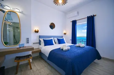 a bedroom with a bed and a mirror and a window at Kiani Akti in Porto Rafti