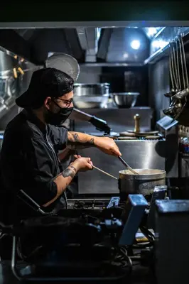 a man stirring a pot in a kitchen at Kiani Akti in Porto Rafti