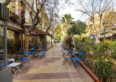 a sidewalk with blue chairs and tables on a street at Athens Lodge in Koukaki in Athens