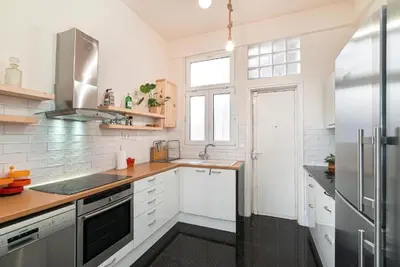 a kitchen with white cabinets and a stainless steel refrigerator at Spacious & Artistic Retro 2BD Apt with SAUNA in Athens