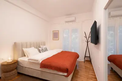 a white bedroom with a bed with an orange blanket at Cozy & Stylish 2BR Home Near Kallimarmaro in Athens