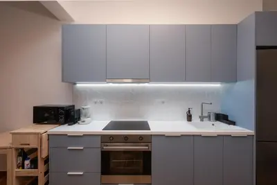 a kitchen with white cabinets and a stove top oven at Cozy & Stylish 2BR Home Near Kallimarmaro in Athens