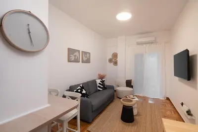 a living room with a couch and a clock on the wall at Cozy & Stylish 2BR Home Near Kallimarmaro in Athens