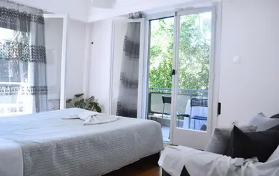 a white bedroom with a bed and a balcony at Alice's Apartment - Athens, Ελλάδα in Athens