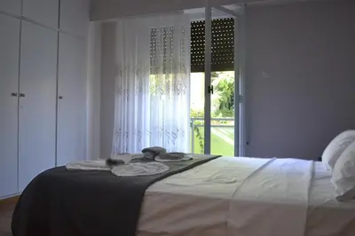 a white bedroom with a bed with a window at Alice's Apartment - Athens, Ελλάδα in Athens