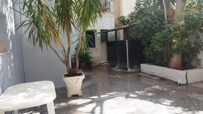 a patio with a palm tree and a white chair at Kallithea Athens Star in Athens