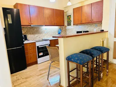 a kitchen with wooden cabinets and a black refrigerator at Urban Acropolis Apartment With Fast internet in Athens