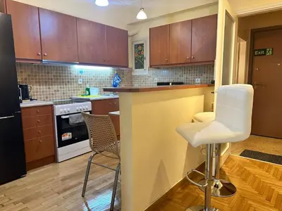 a kitchen with wooden cabinets and white chairs at Urban Acropolis Apartment With Fast internet in Athens