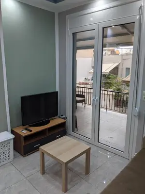a living room with a flat screen tv and a table at Athens Kallithea Apartment in Athens