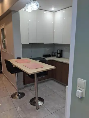 a kitchen with a table with two chairs and white cabinets at Athens Kallithea Apartment in Athens