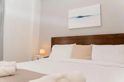 a bedroom with a white bed with a wooden headboard at 1400ft Central Rooftop Gym King Bed WFH in Athens