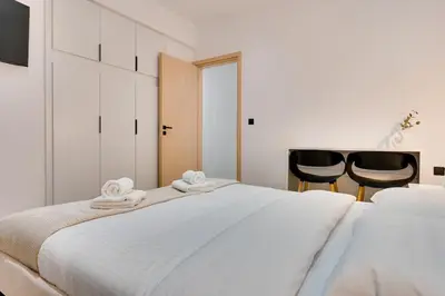 a bedroom with two white beds and two black chairs at CityLife apartment 2'from metaxourgio station 2B in Athens