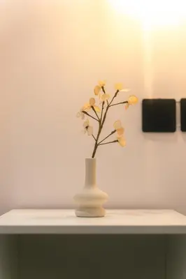a white vase with yellow flowers in it on a shelf at CityLife studio 2'from metaxourgio station 2A in Mesochórion