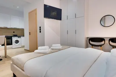 a white bedroom with a large bed and two black chairs at CityLife studio 2'from metaxourgio station 2A in Mesochórion