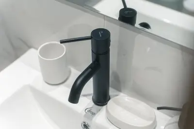 a bathroom sink with a black faucet and a toilet at CityLife studio 2'from metaxourgio station 2A in Mesochórion