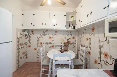 a kitchen with white cabinets and a table and chairs at PS Apartment in Athens