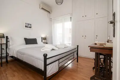 a white bedroom with a bed and a desk at PS Apartment in Athens