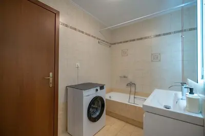 a bathroom with a washing machine next to a bath tub at Sunlit Terrace 3BR Apartment - Tavros by ΜΡS in Athens