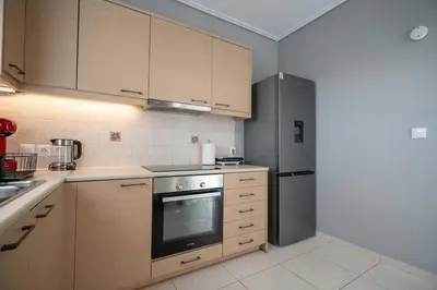 a kitchen with wooden cabinets and a stainless steel refrigerator at Sunlit Terrace 3BR Apartment - Tavros by ΜΡS in Athens