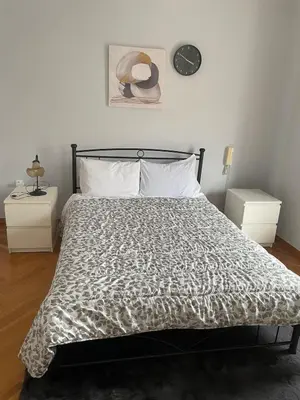 a bed in a bedroom with two tables and a clock at 45 τμ διαμέρισμα in Athens