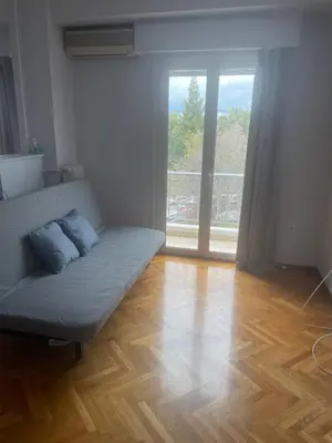 a living room with a couch and a large window at 45 τμ διαμέρισμα in Athens